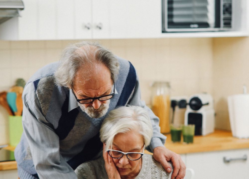 An elderly couple reviewing financial documents together at their kitchen table